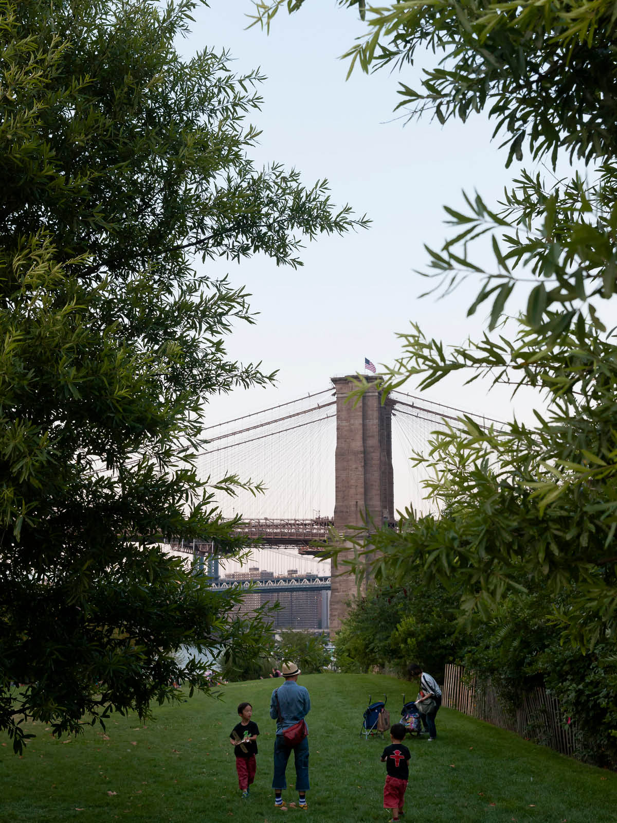 Family playing Pier 1 Lawn with Brooklyn Bridge in the distance.