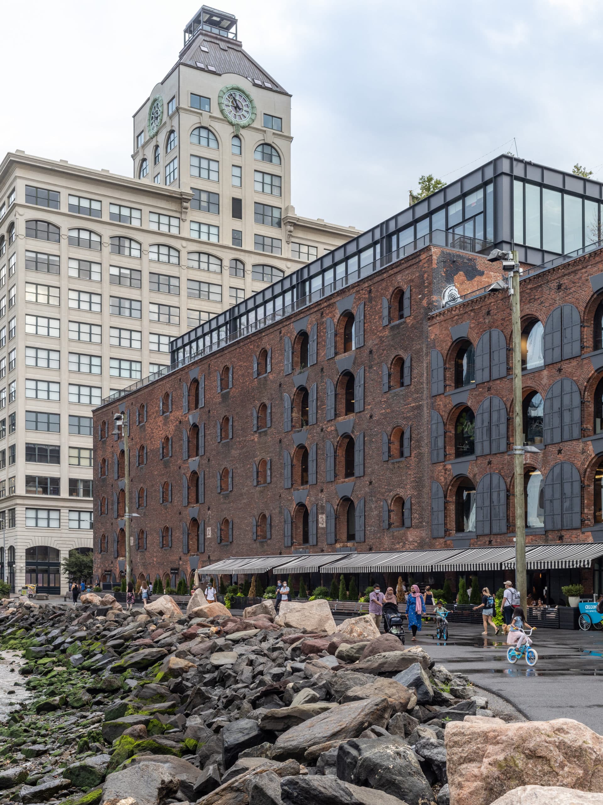 View of the Empire Stores from stones by the water on a cloudy day.