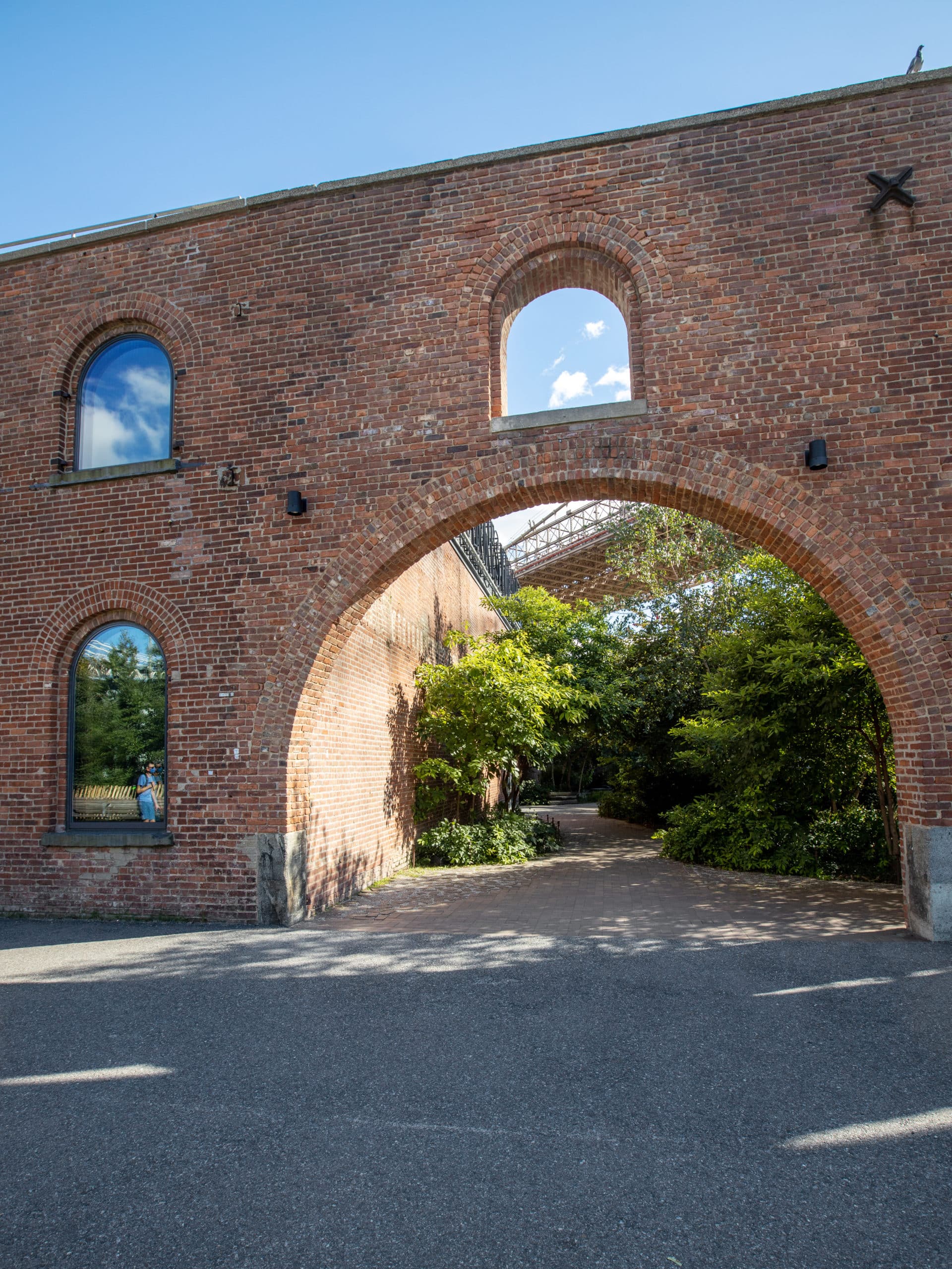 Looking through the brick archway at tree-lined path in the Max Family Garden.