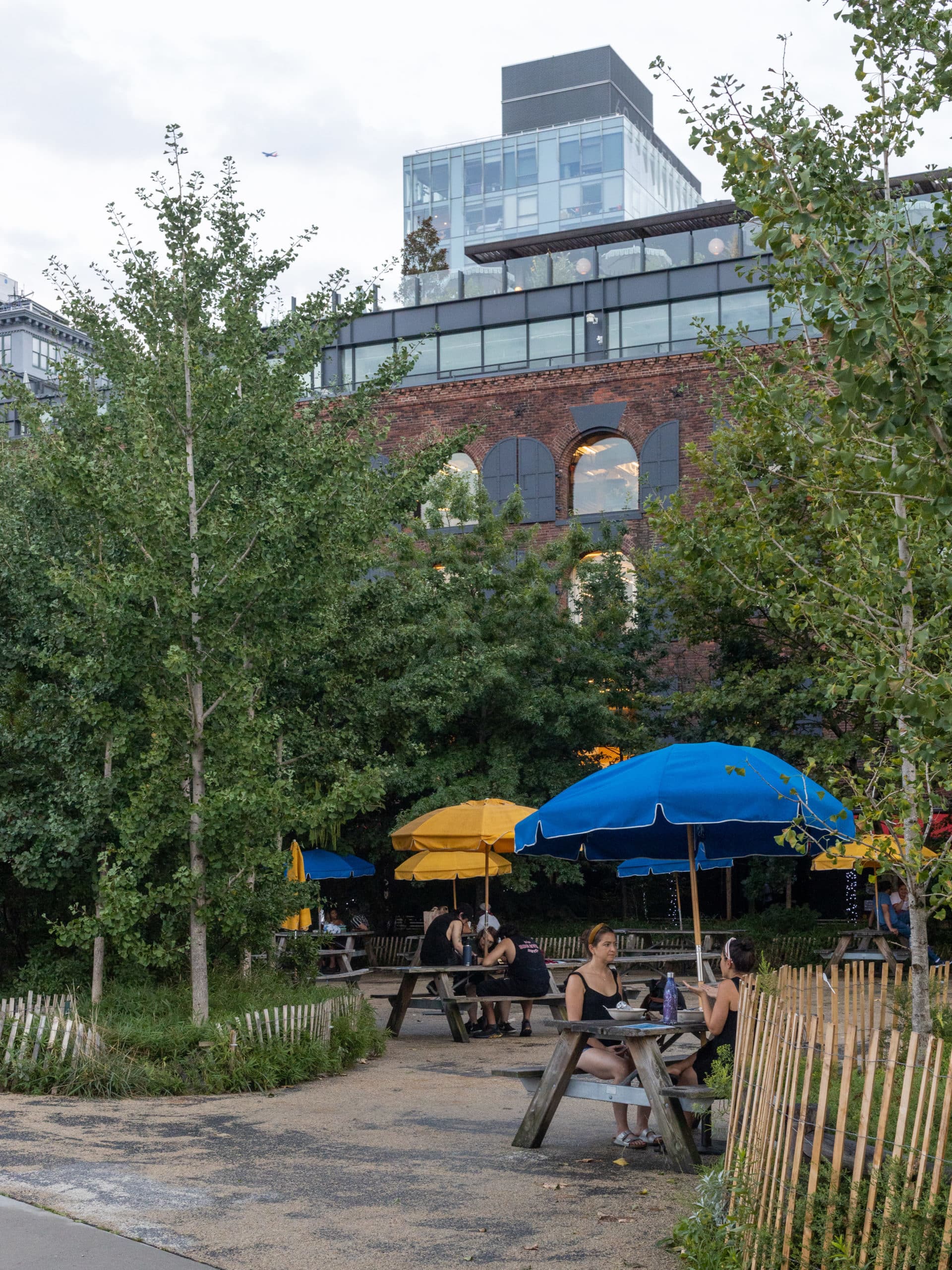 People eating at benches in the Picnic Grove with historic building in the background.