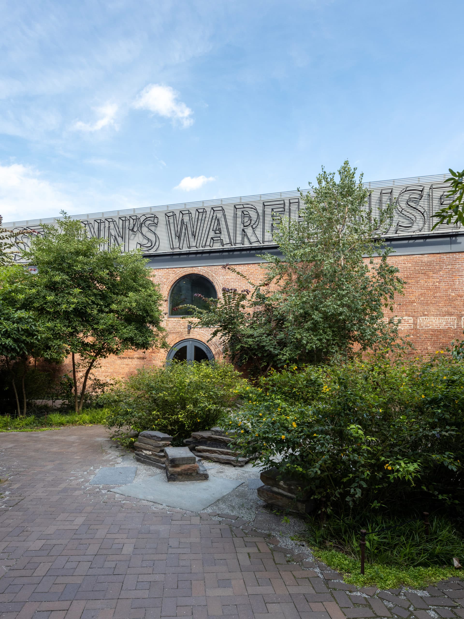 Exterior of St Ann's Warehouse with a small garden in the foreground on a sunny day.