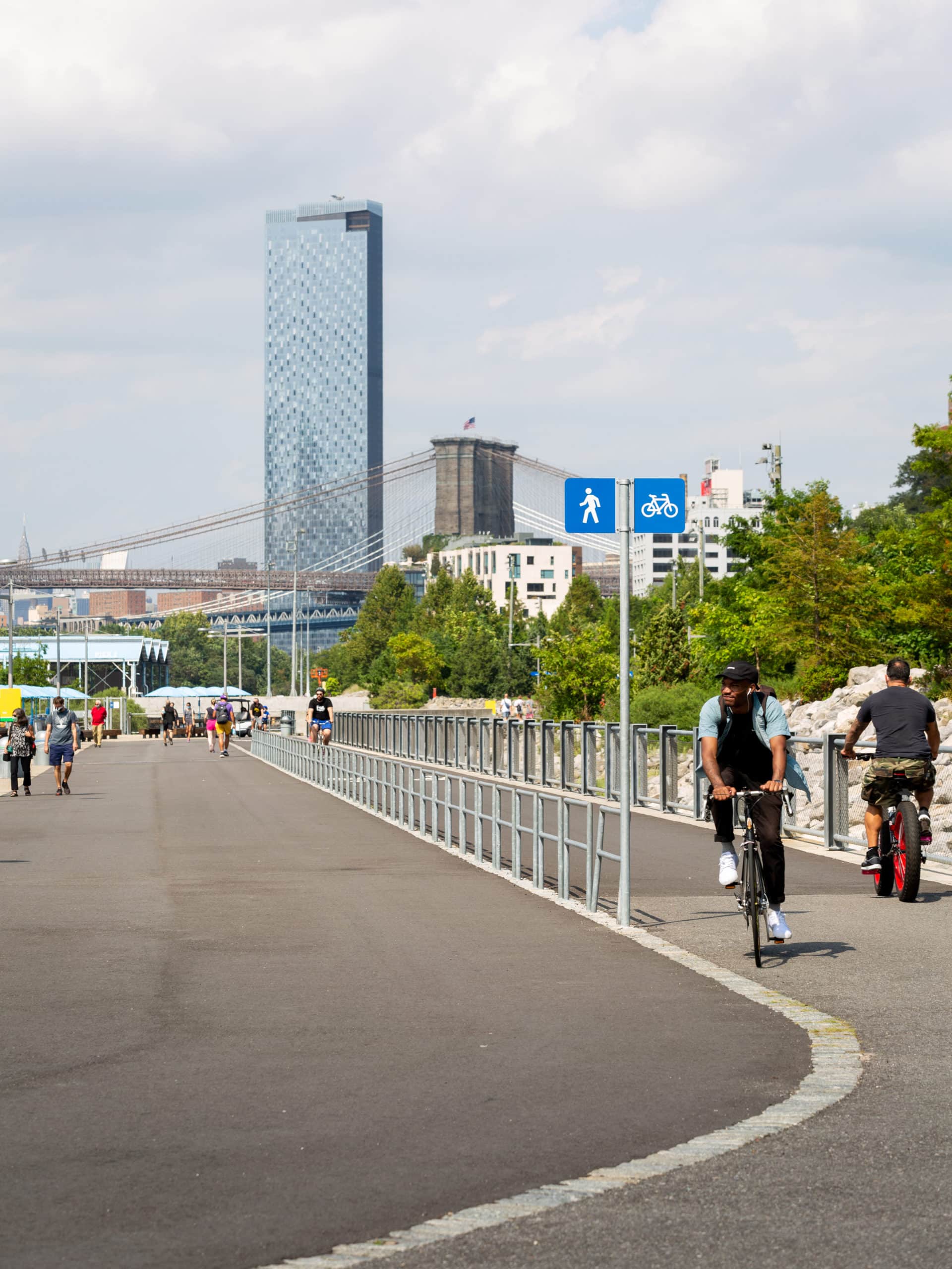 Bike and Pedestrian paths on the Greenway on a sunny day. The Brooklyn Bridge and One Manhattan Square are seen in the background.