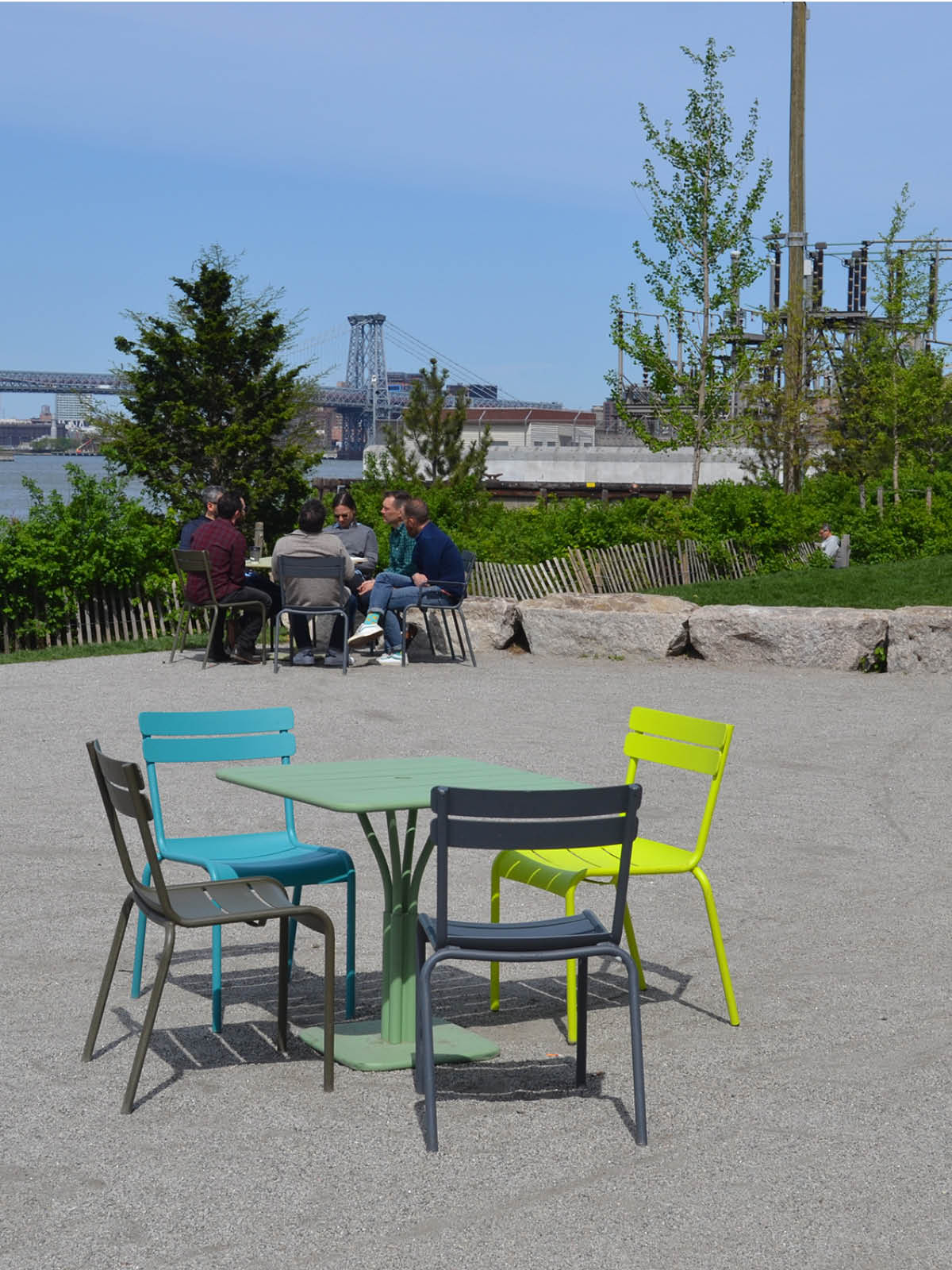 Tables and chairs with a group sitting in the distance on the John Street terrace on a sunny day.