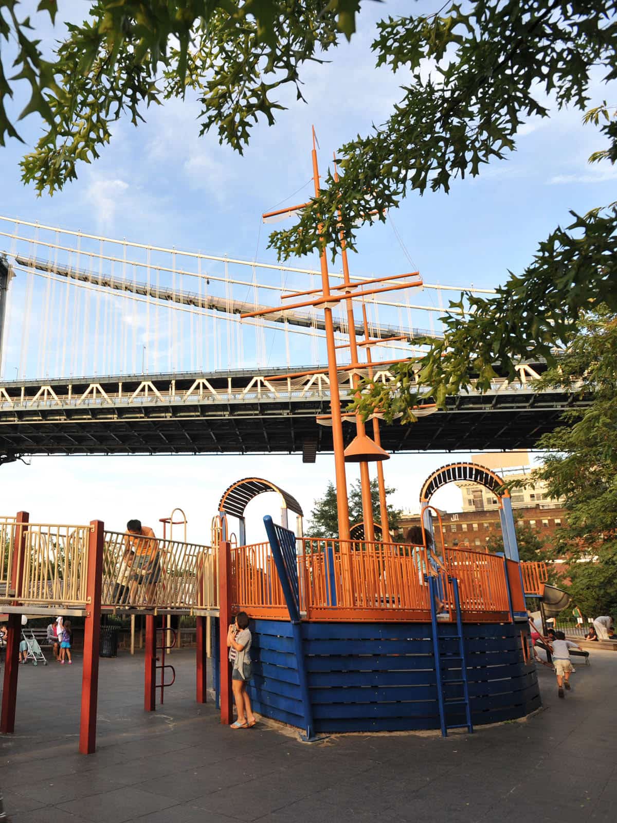 Children playing on a pirate ship themed playground structure on a sunny day.