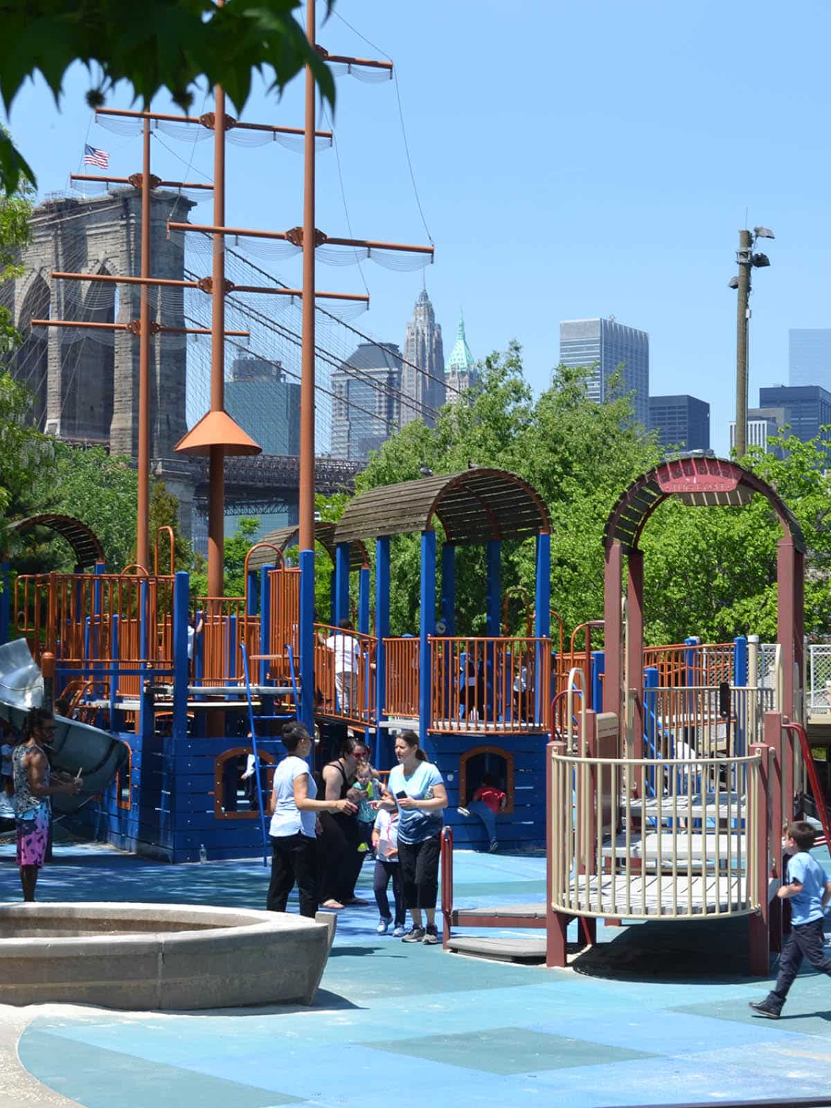 Children playing on a pirate ship themed playground structure on a sunny day.