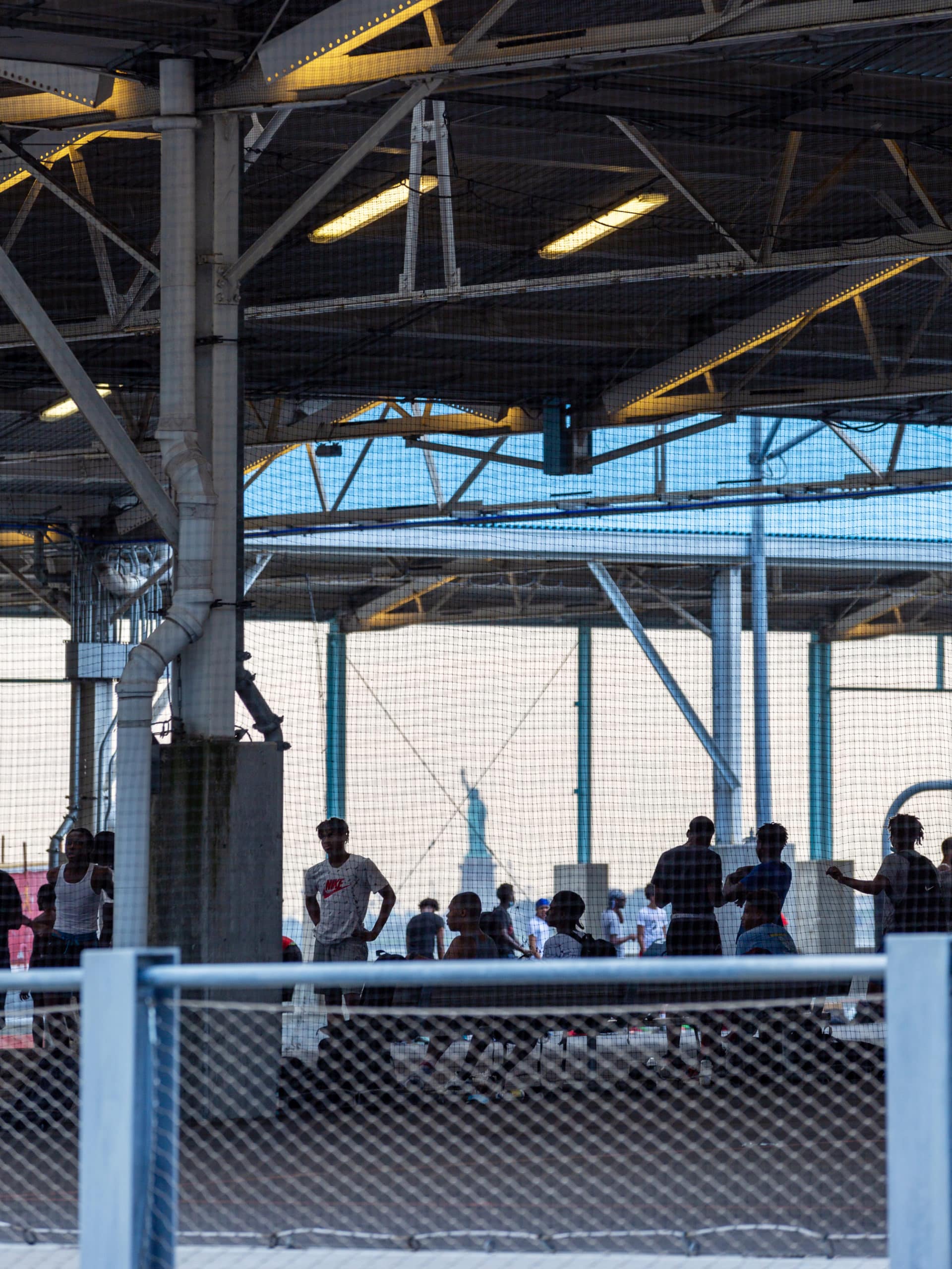 People watching a basketball game in Pier 2's covered basketball courts on a cloudy day.