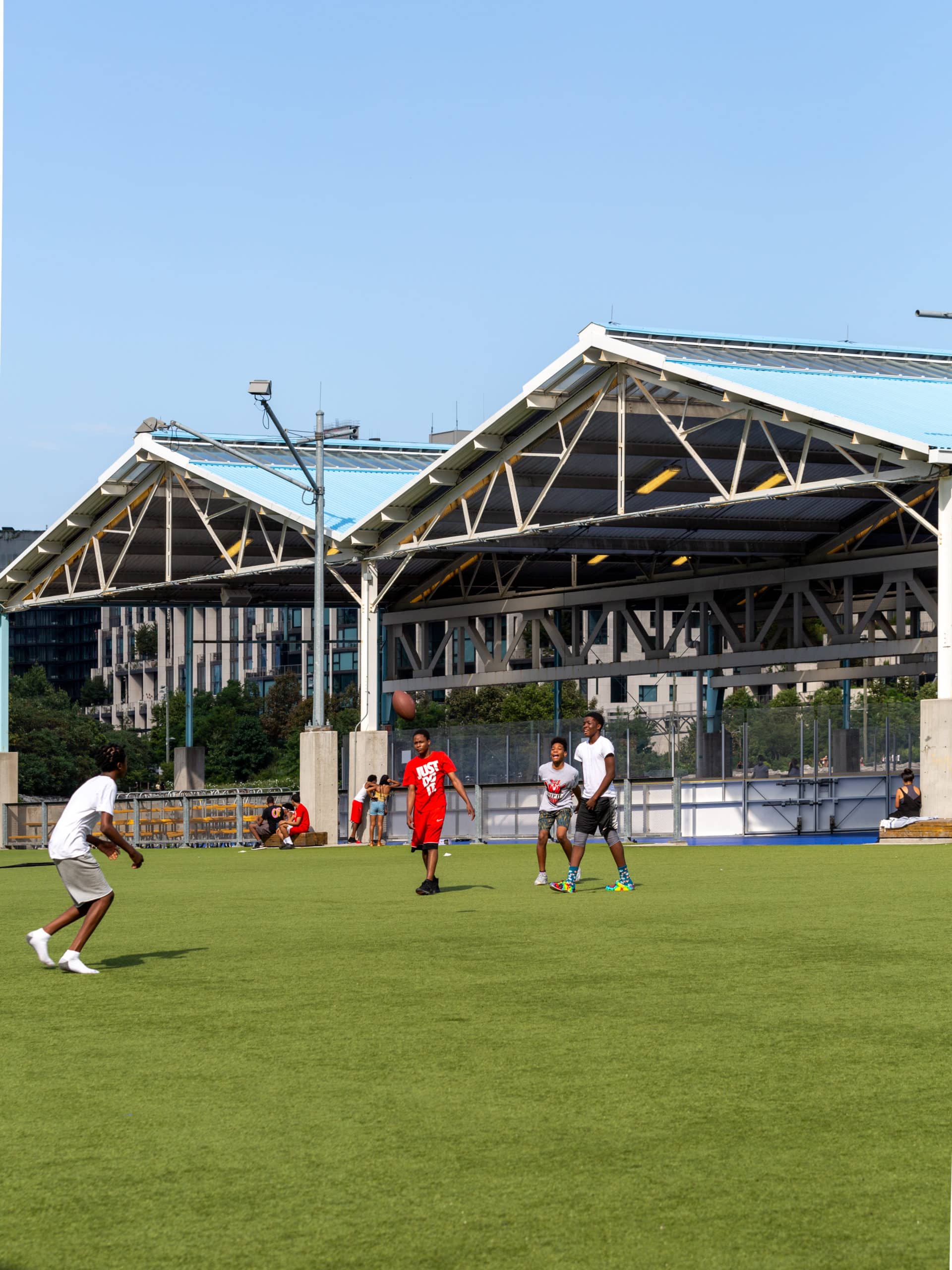 Group of boys playing football on the Pier 2 Play Turf on a sunny day.