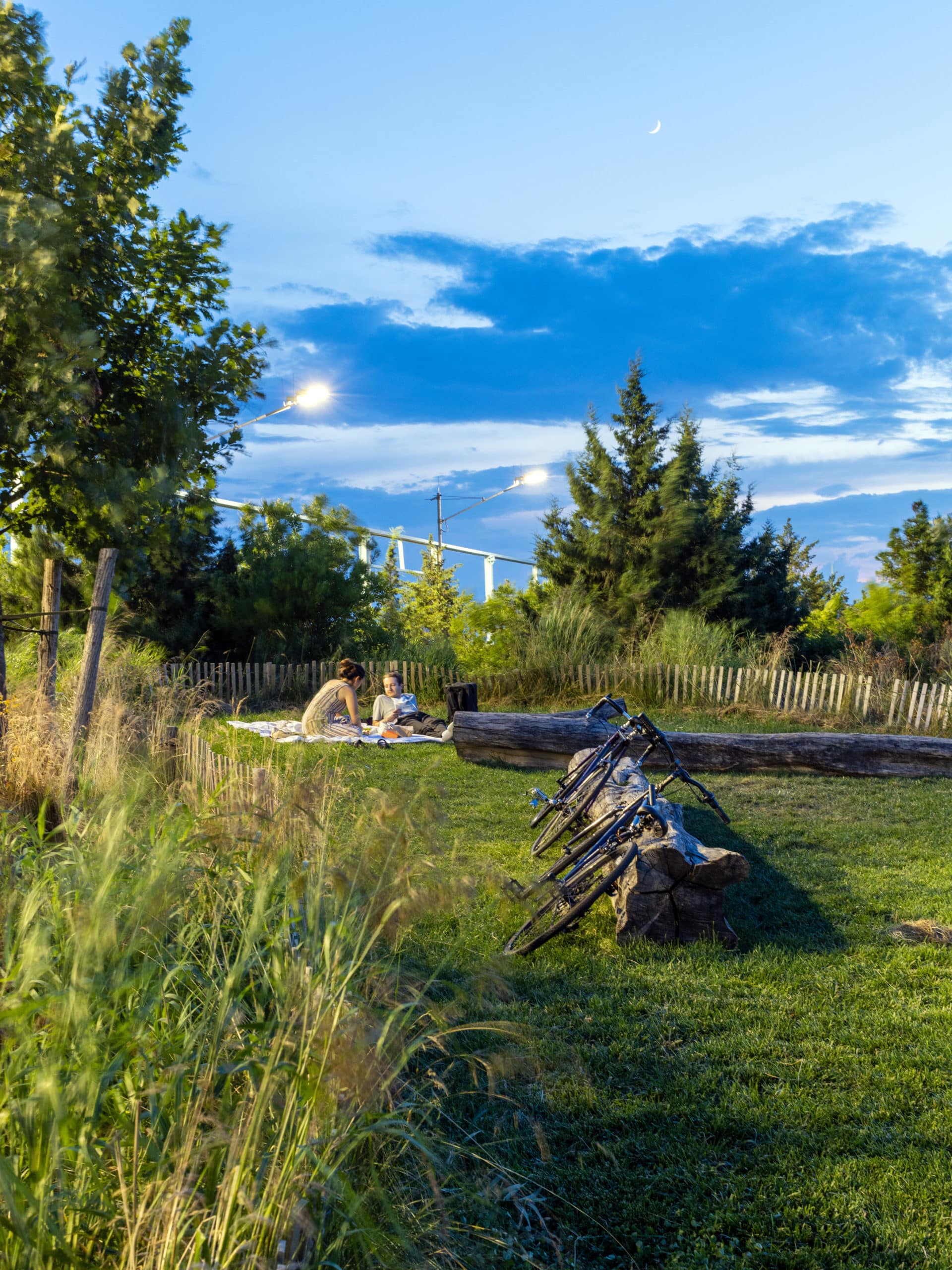 Couple sitting on the lawn with two bikes resting on a log at night.