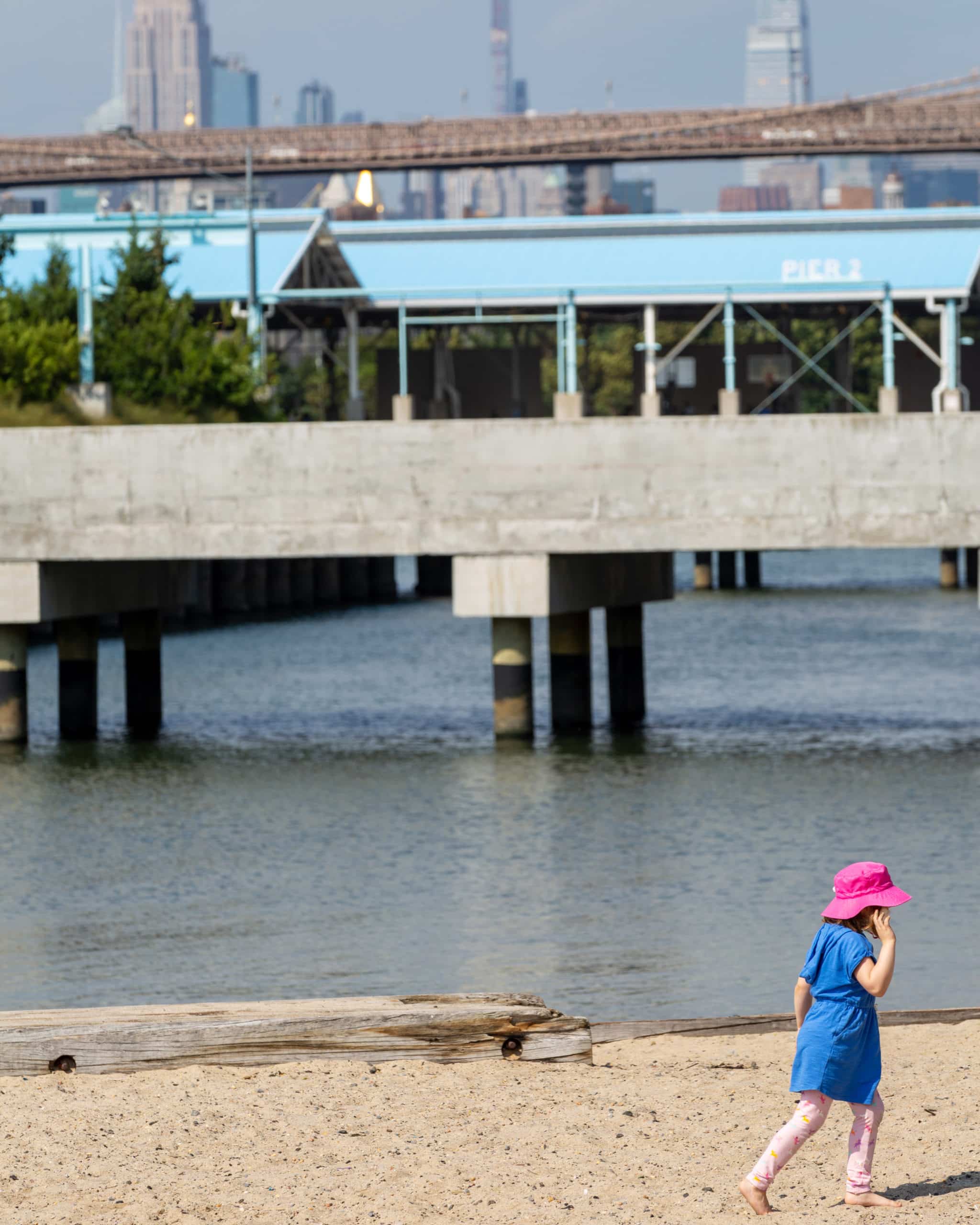 Child walking on the Pier 4 Beach on a sunny day, with Pier 3 in the background.