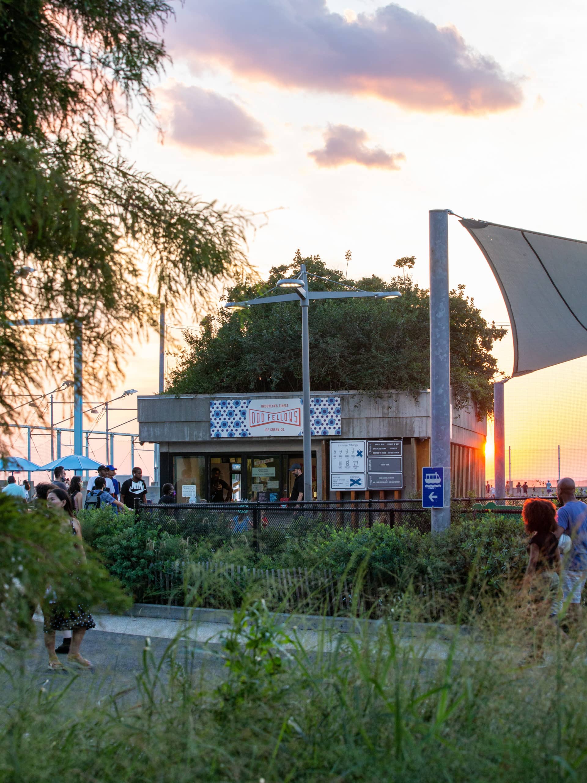 View from pathway of people lined up for OddFellows Ice Cream Co. at sunset