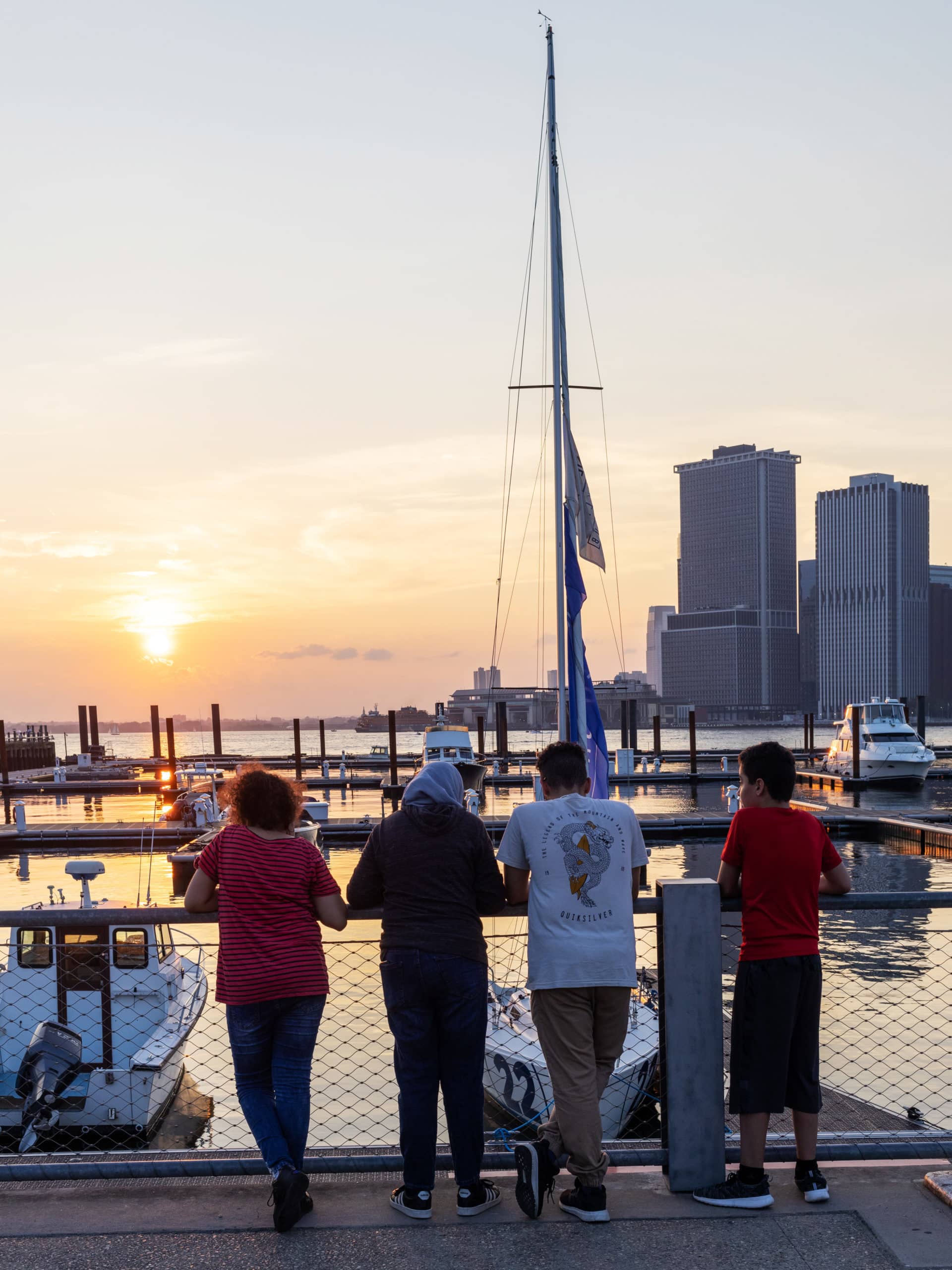 People on pathway looking at the sailboats at ONE°15 Brooklyn Marina at sunset.