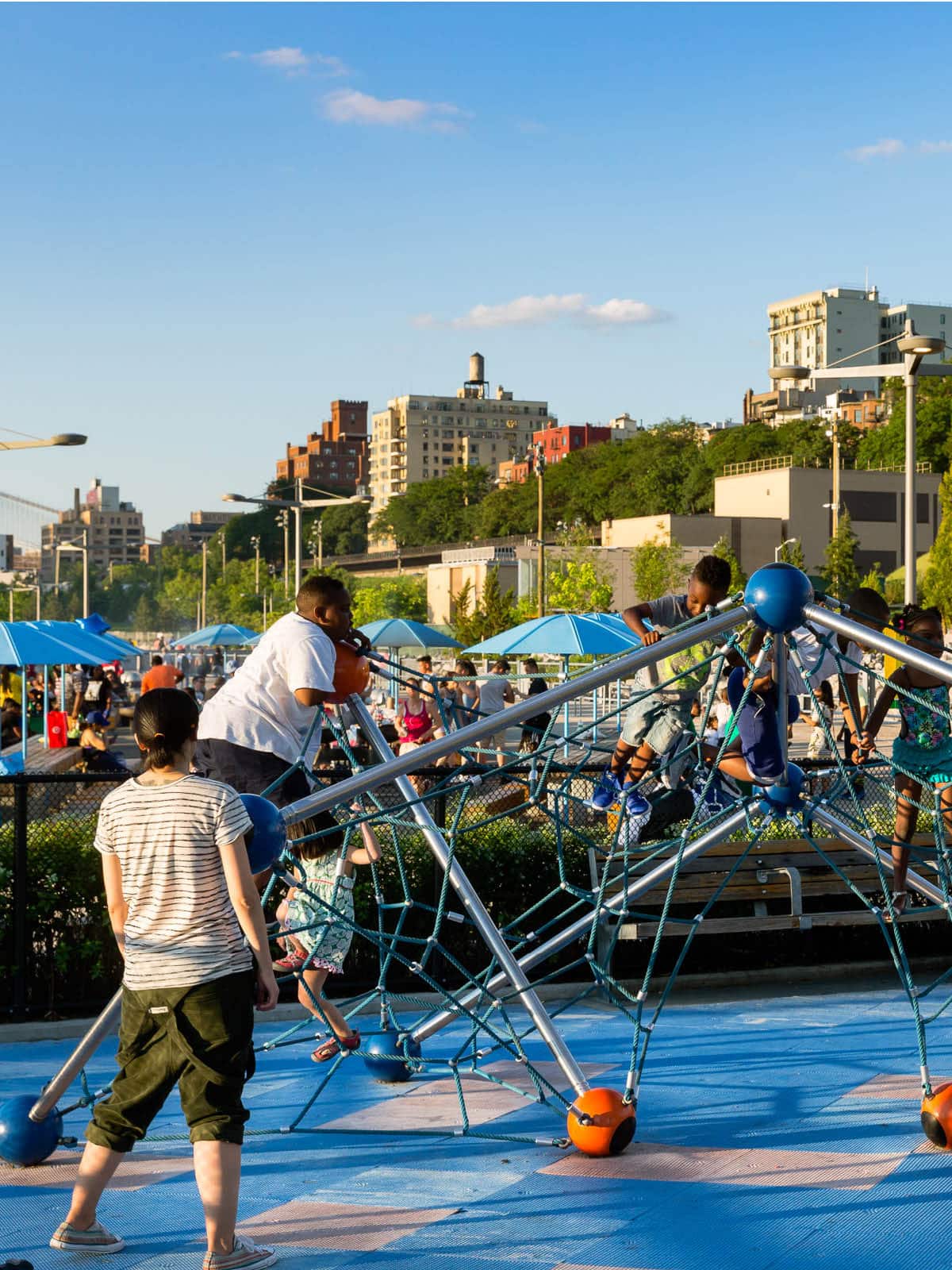 Children climbing on a playground structure with picnic area in the background at sunset.