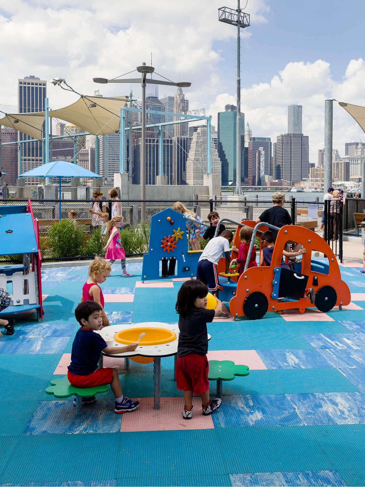 Children playing in a playground under a canopy on a cloudy day.