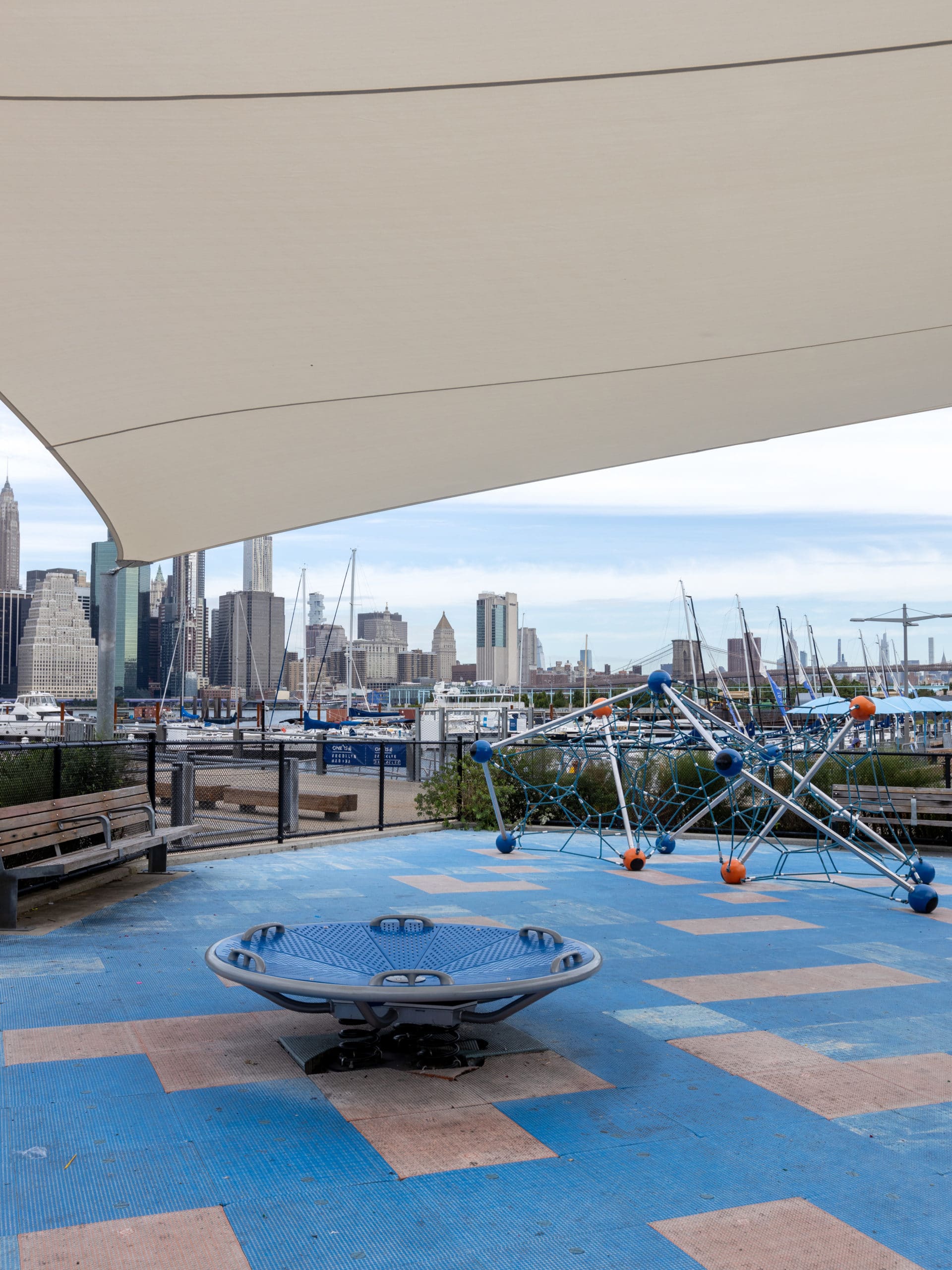 Pier 5 Playground underneath a canopy with view of marina and lower Manhattan.