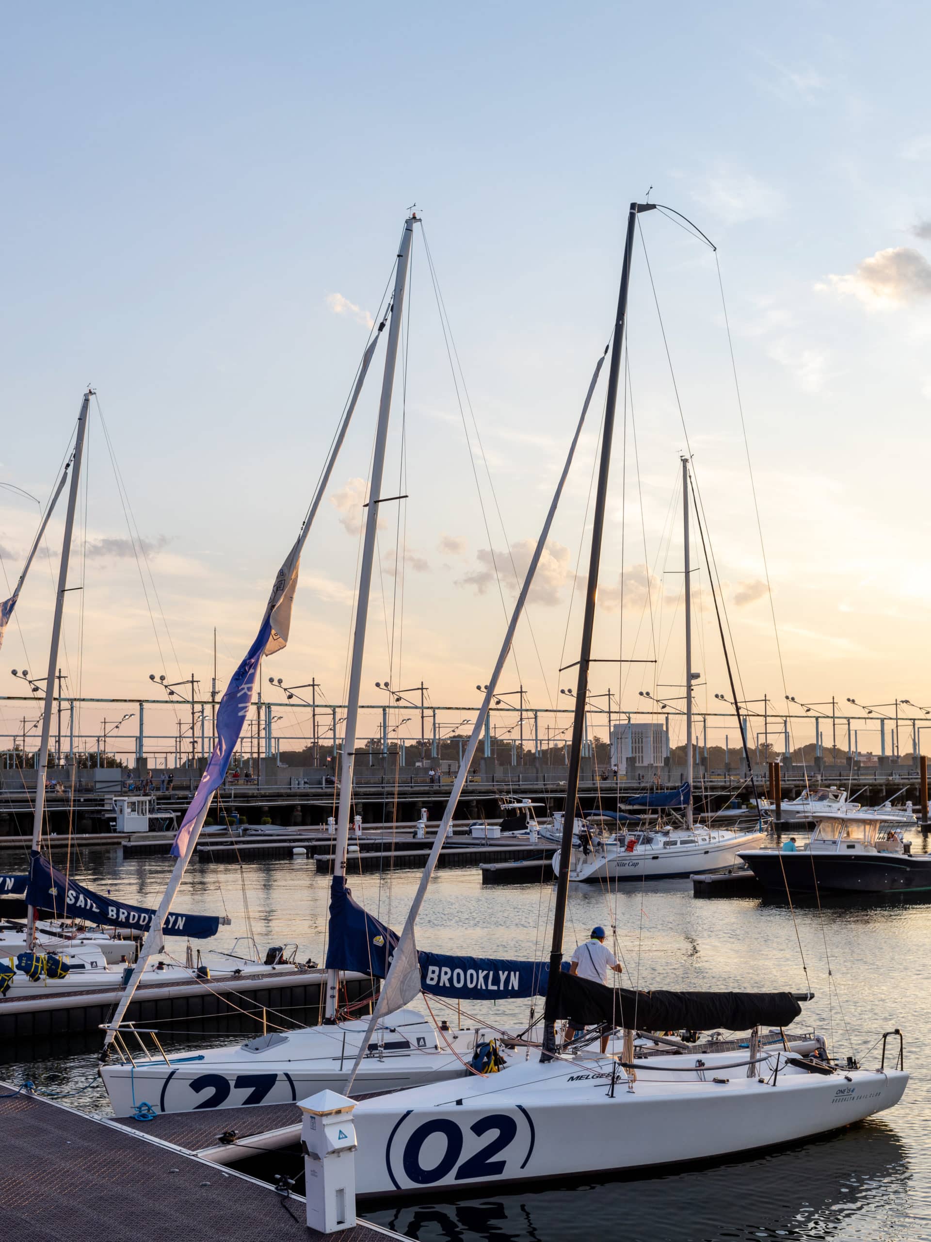 Man on docked sailboat at ONE°15 Brooklyn Marina at Pier 5 at sunset