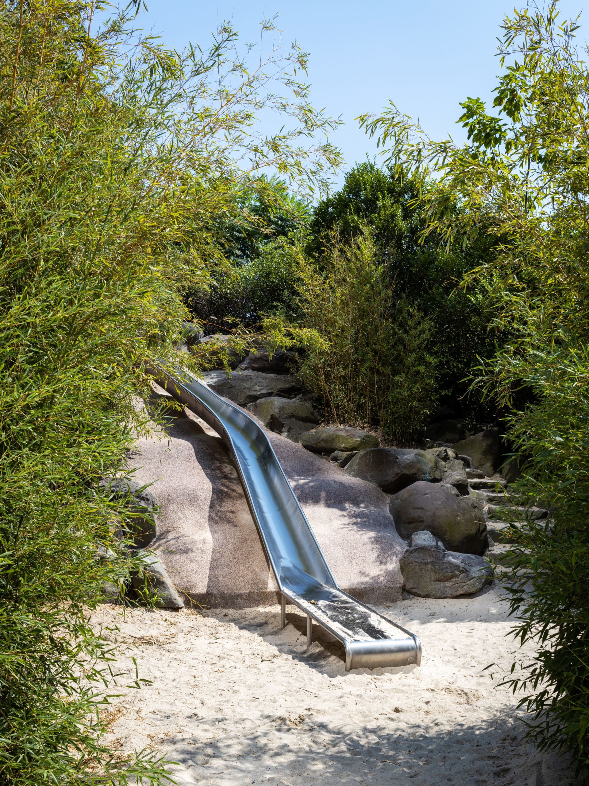 Long metal slide surrounded by trees in Slide Mountain on a sunny day.