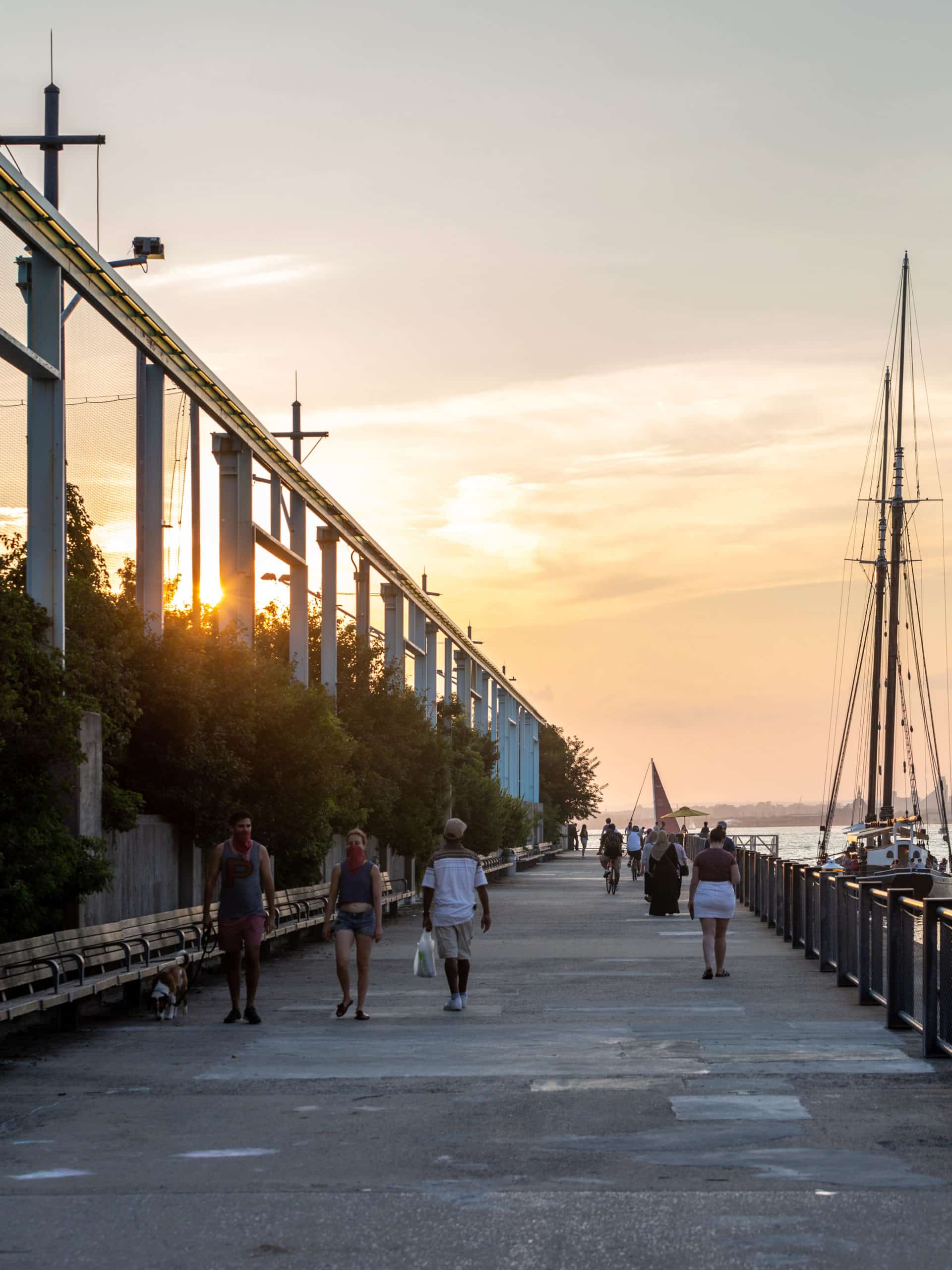 People walking on Pier 6 Promenade at sunset with restaurant boat Pilot to the right.