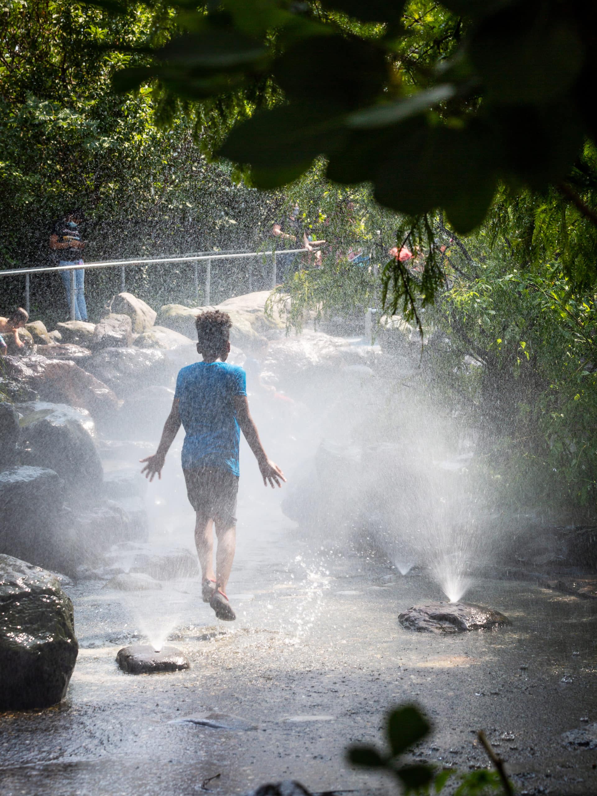 Child jumping in spray at Pier 6 Water Lab on a sunny day.