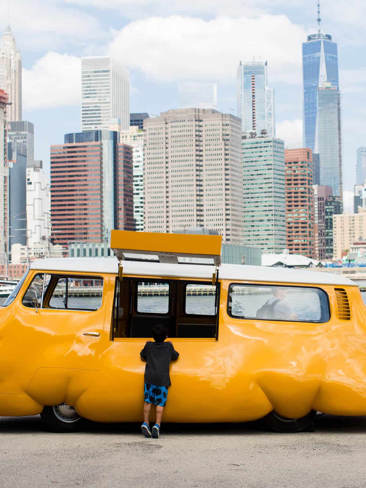 Child looking into Erwin Wurm's Hot Dog Bus on the promenade.