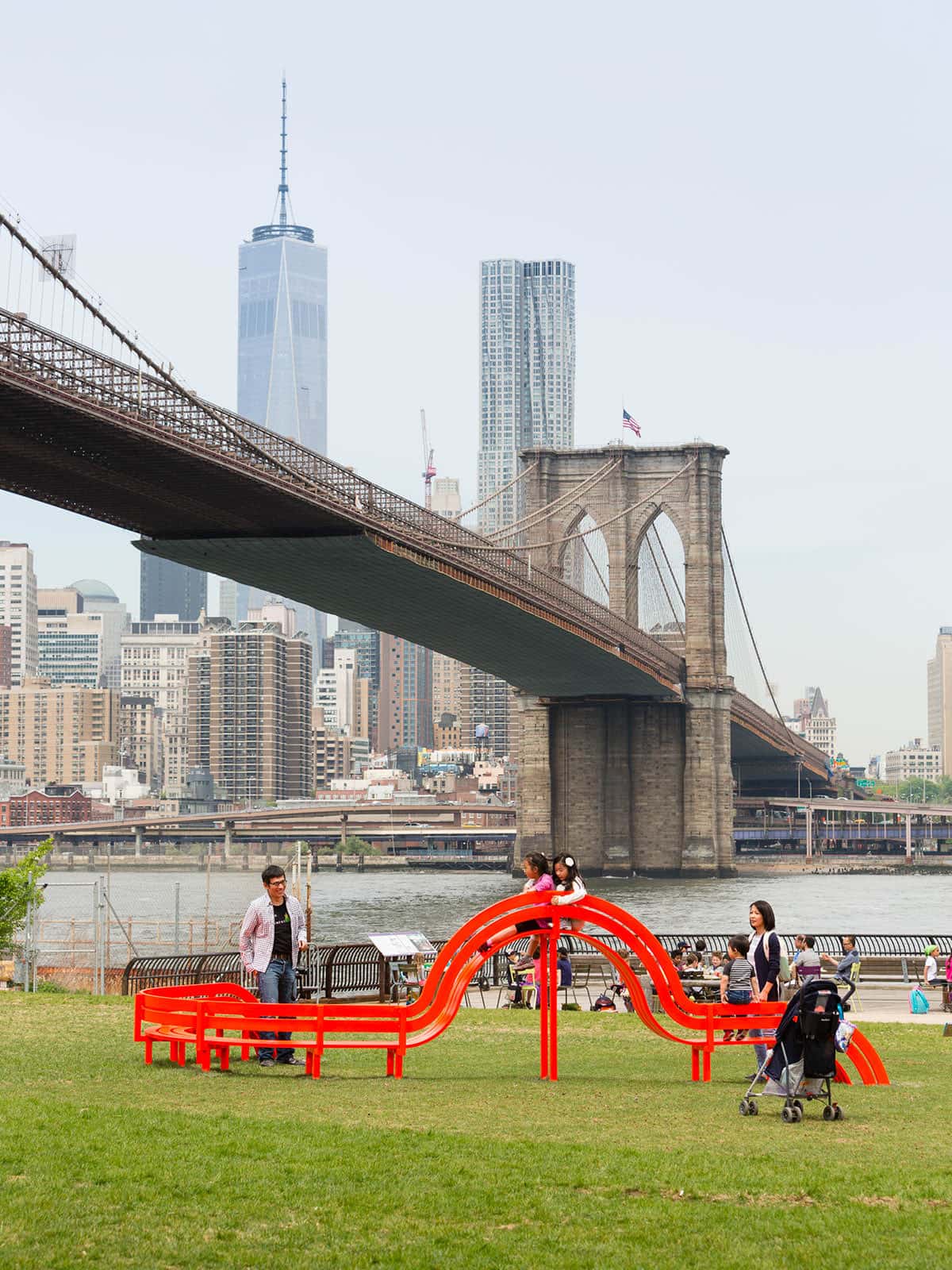 Family climbing on sculptural red bench from Jeppe Hein's Modified Social Bench series.