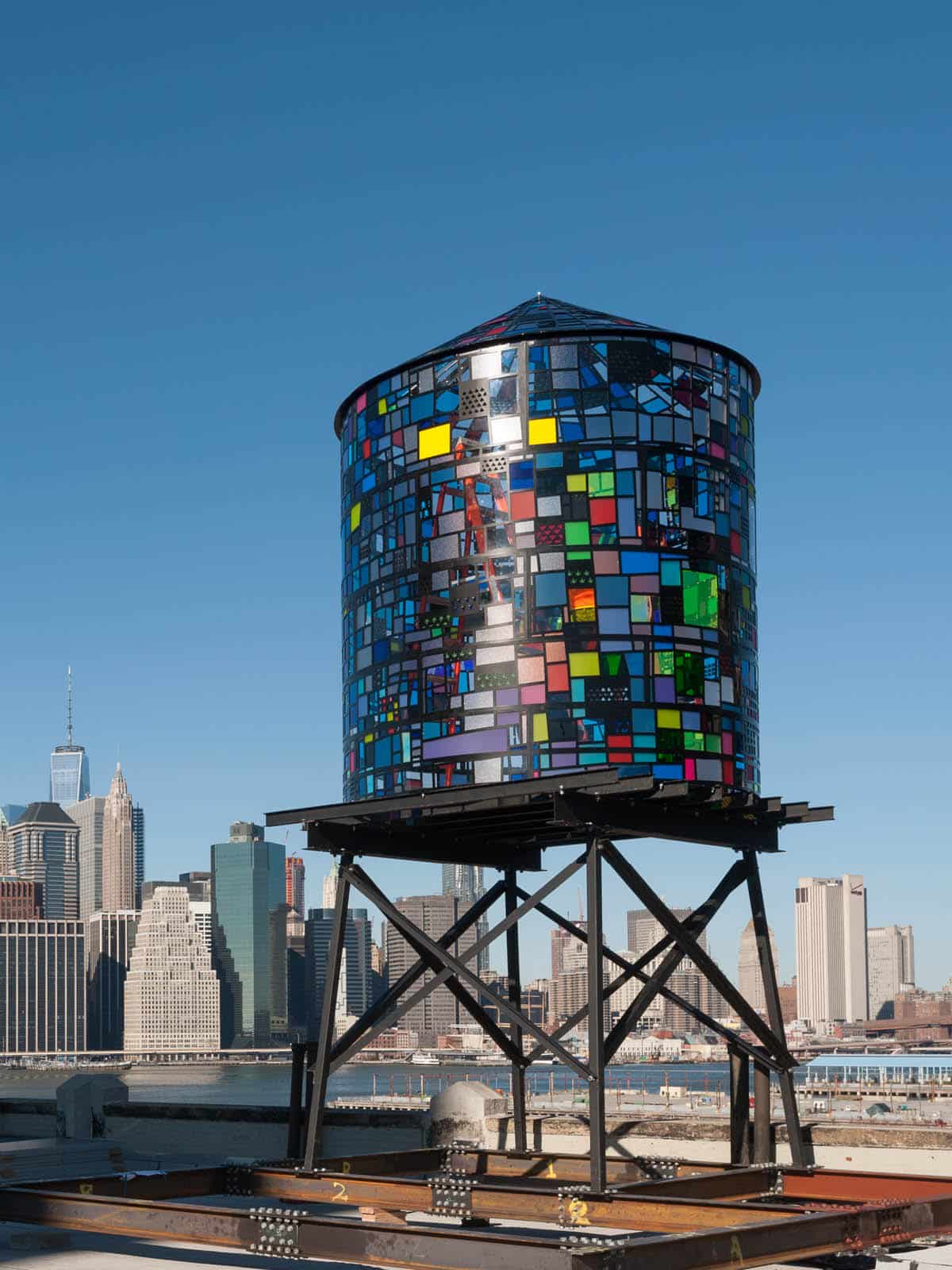 Watertower II by Tom Fruin, a colored plexiglas water tower seen on a sunny day with lower Manhattan in the background.