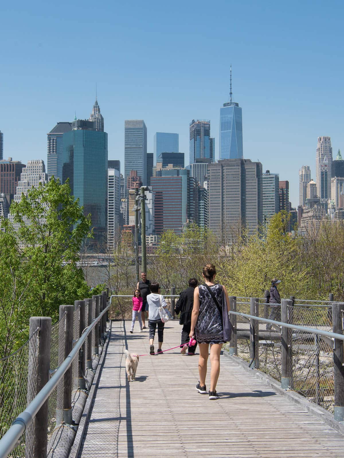 People walking along Squibb Bridge on a sunny day.