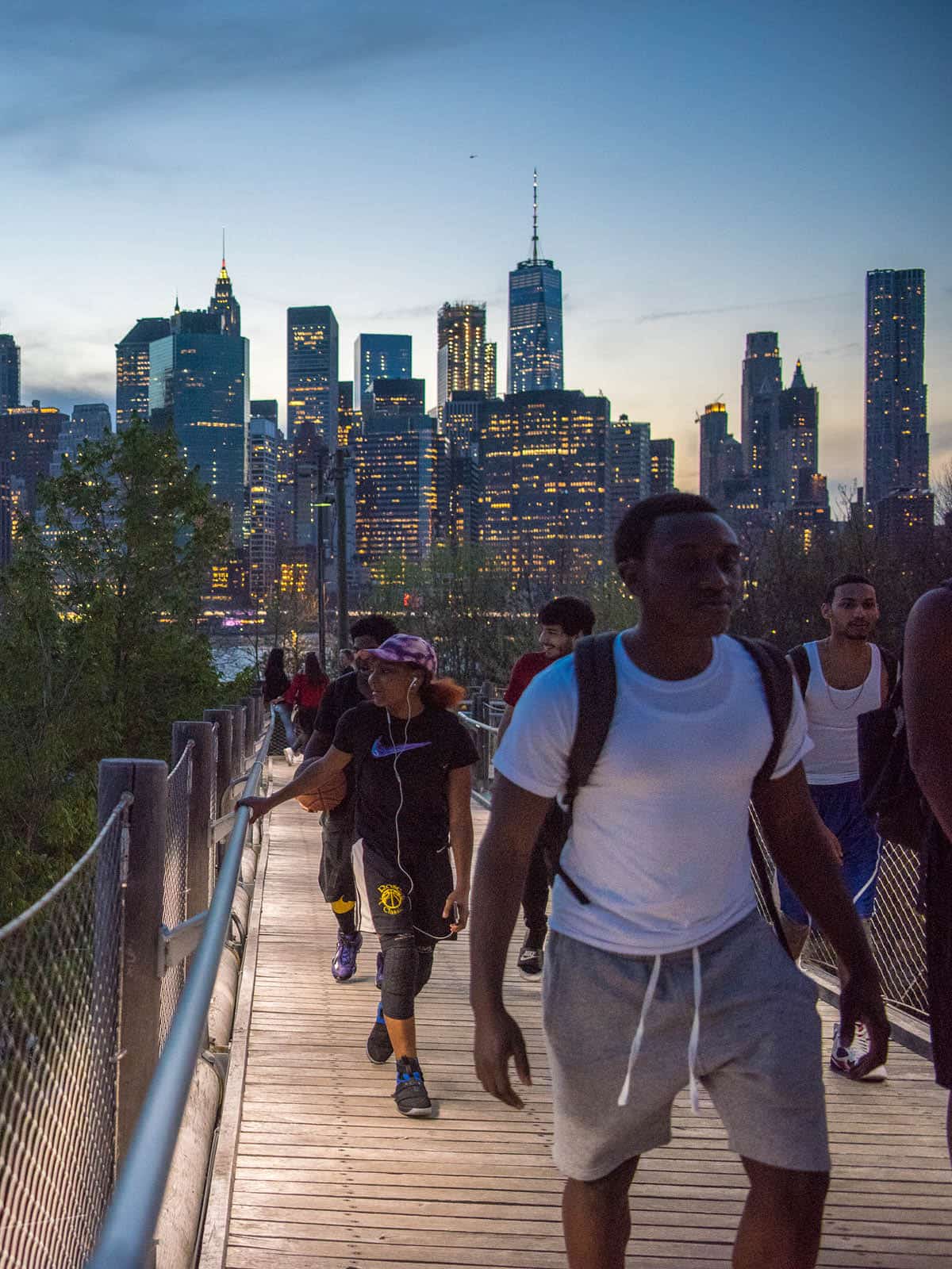 People walking along Squibb Bridge at dusk.