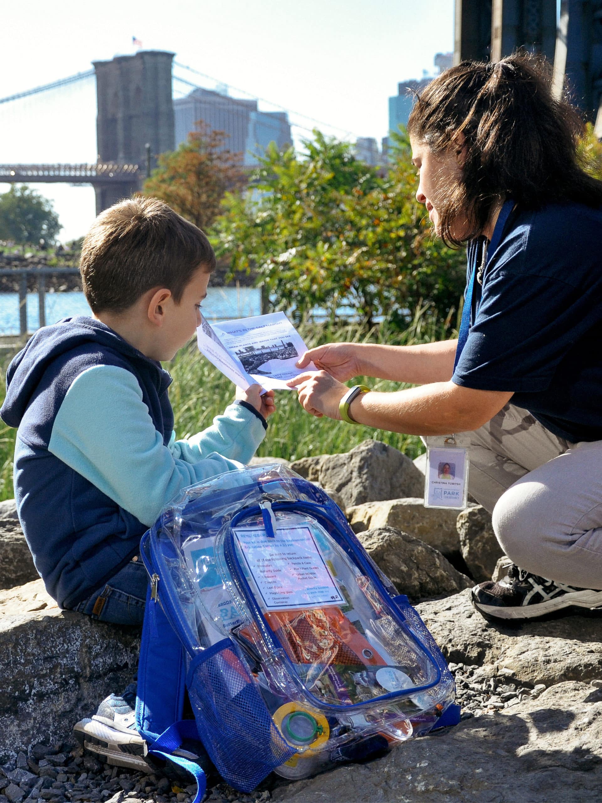 Instructor and child looking at activity book from the Cove Kit on a sunny day.