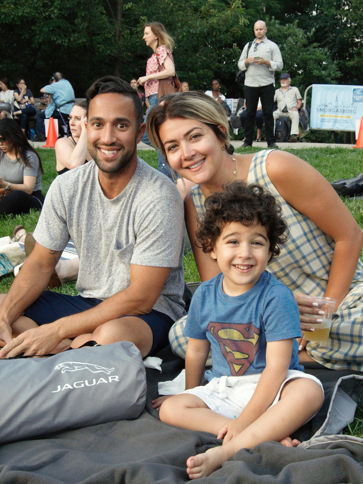 Portrait of family smiling and sitting on the lawn waiting to watch a movie.