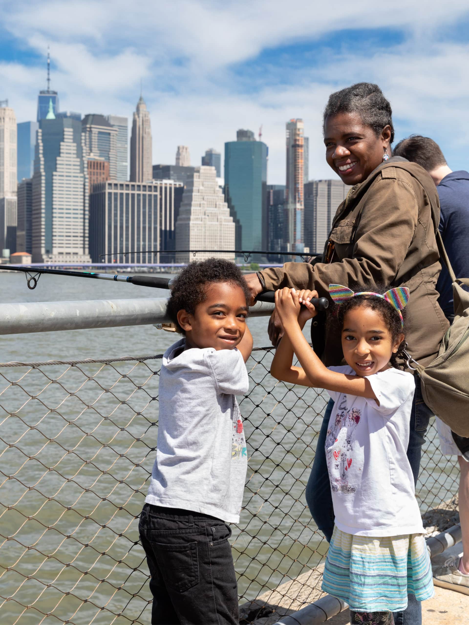 Woman holding a fishing rod with small children on a sunny day.