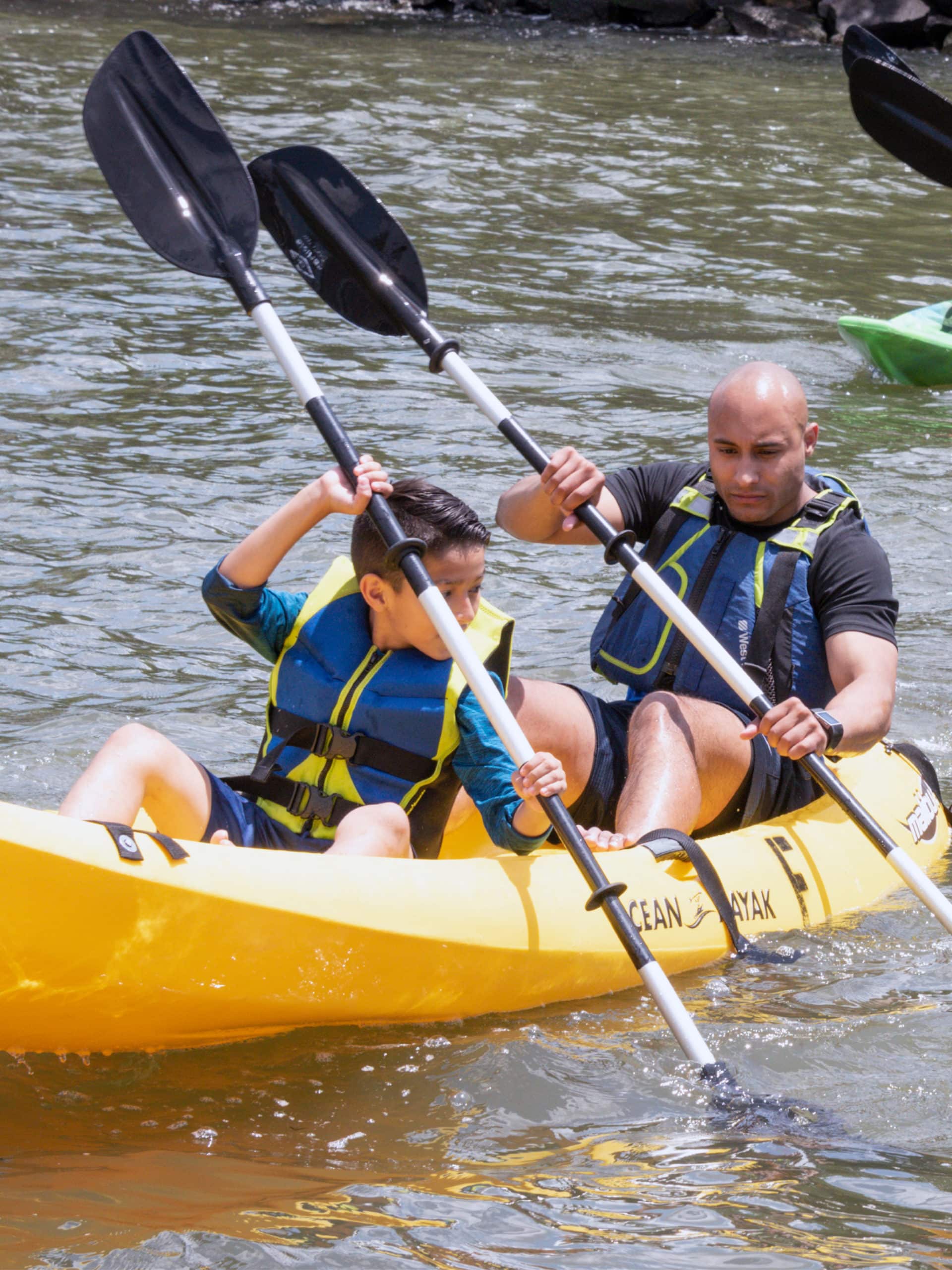 Man and child in a yellow kayak on a sunny day.