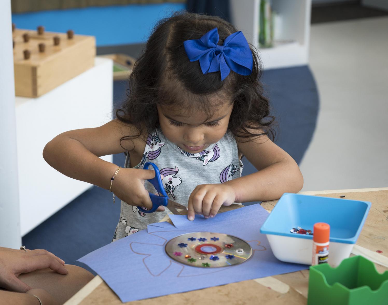 Small girl doing a craft in a classroom.