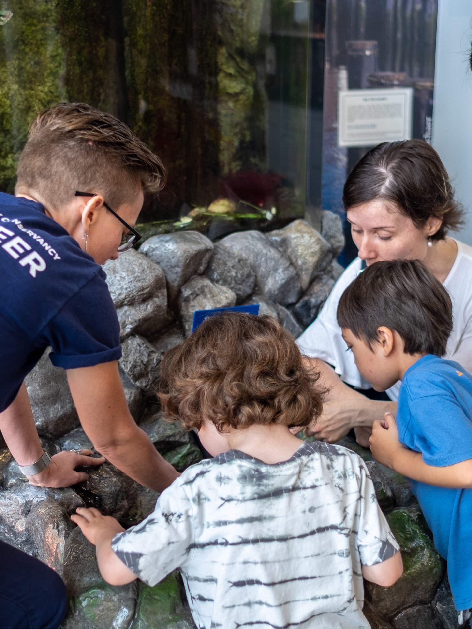 Small boys and adult looking at something held by instructor.