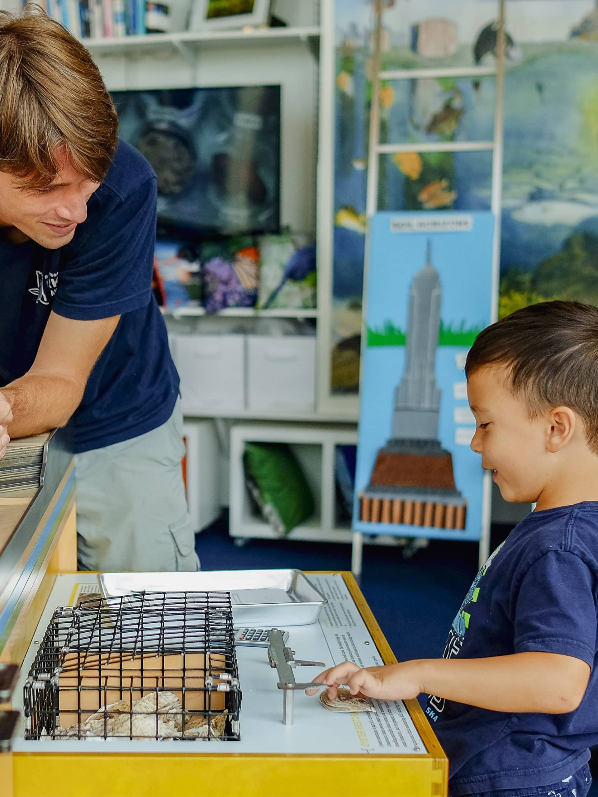 Young boy looking at exhibit with instructor in a classroom.