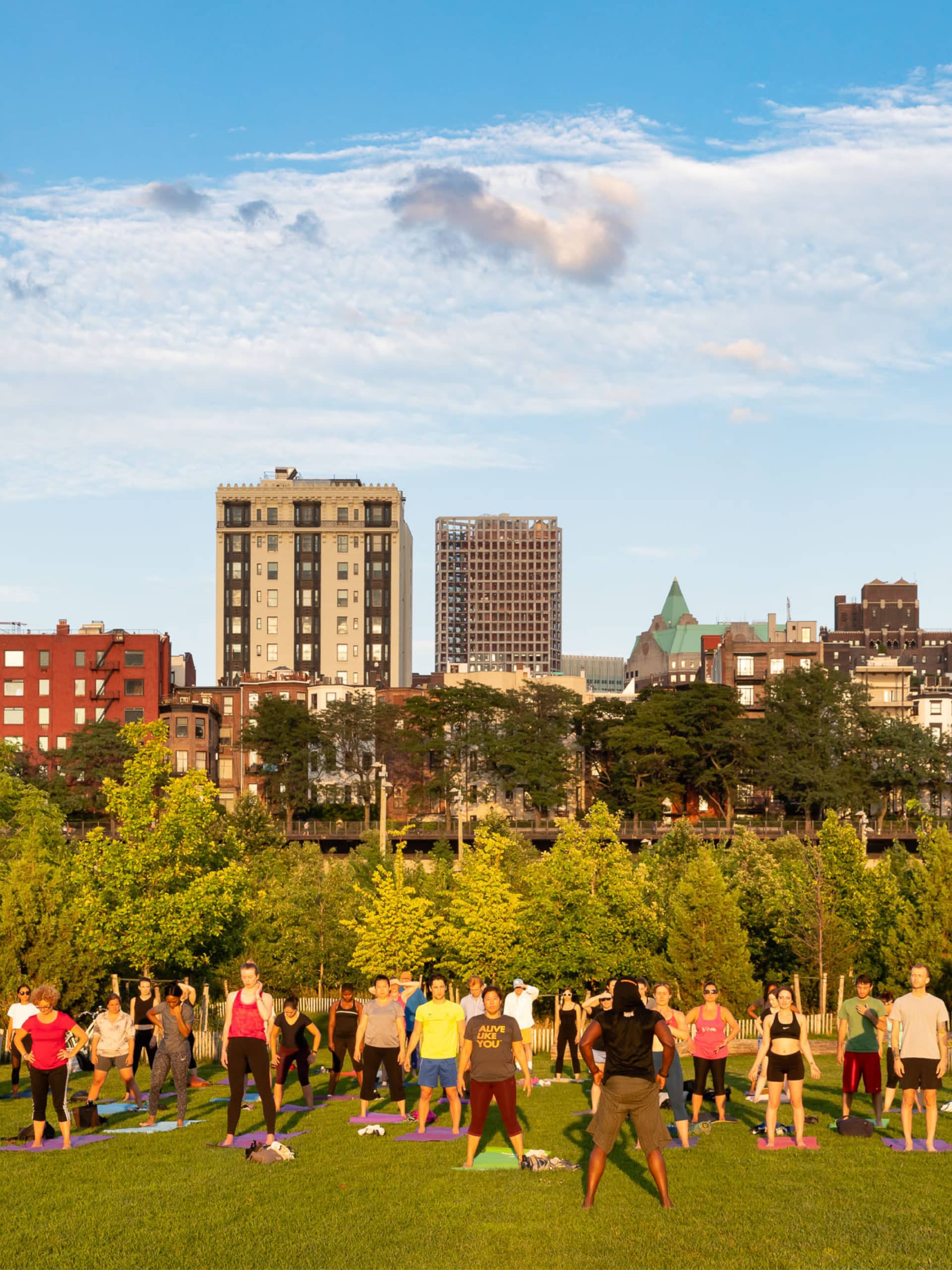 People doing a standing pilates pose facing the sunset.