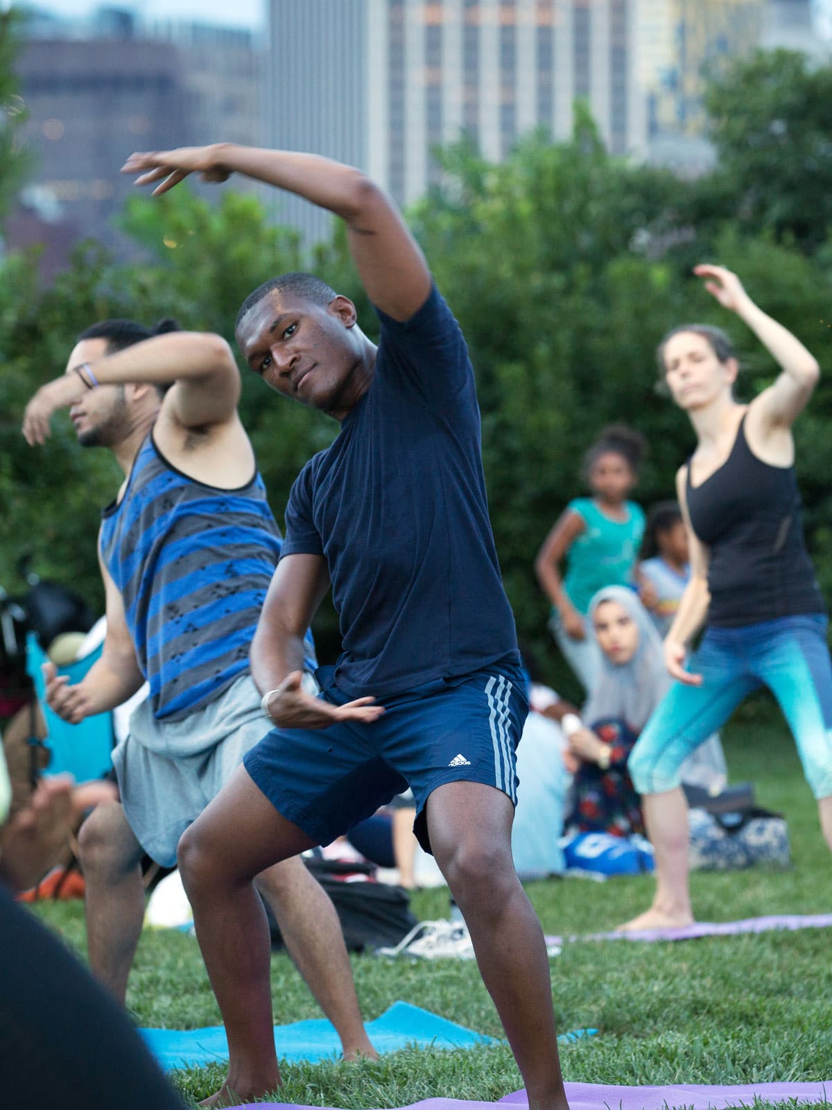 Close up of people doing yoga pose on the lawn at dusk.