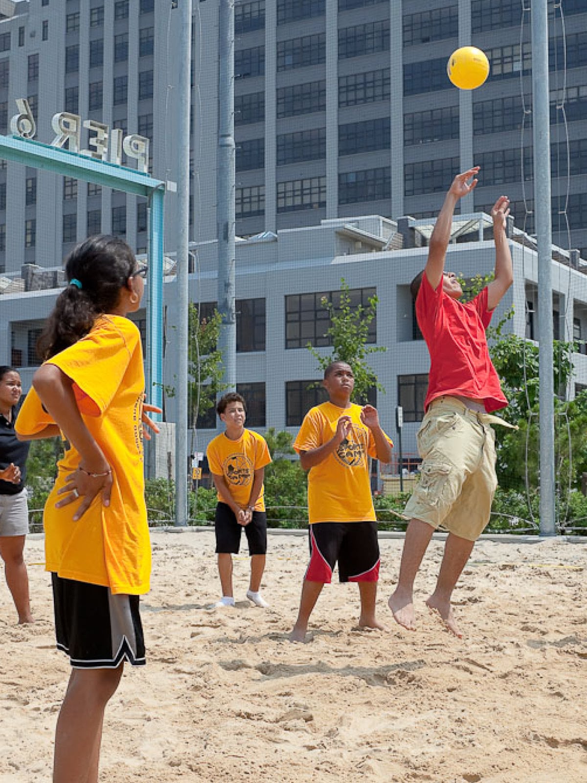 Man jumps to hit ball on a sand court on a sunny day.