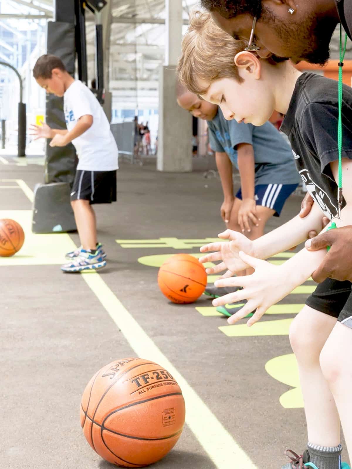 Coach helping young boy hold a basketball.