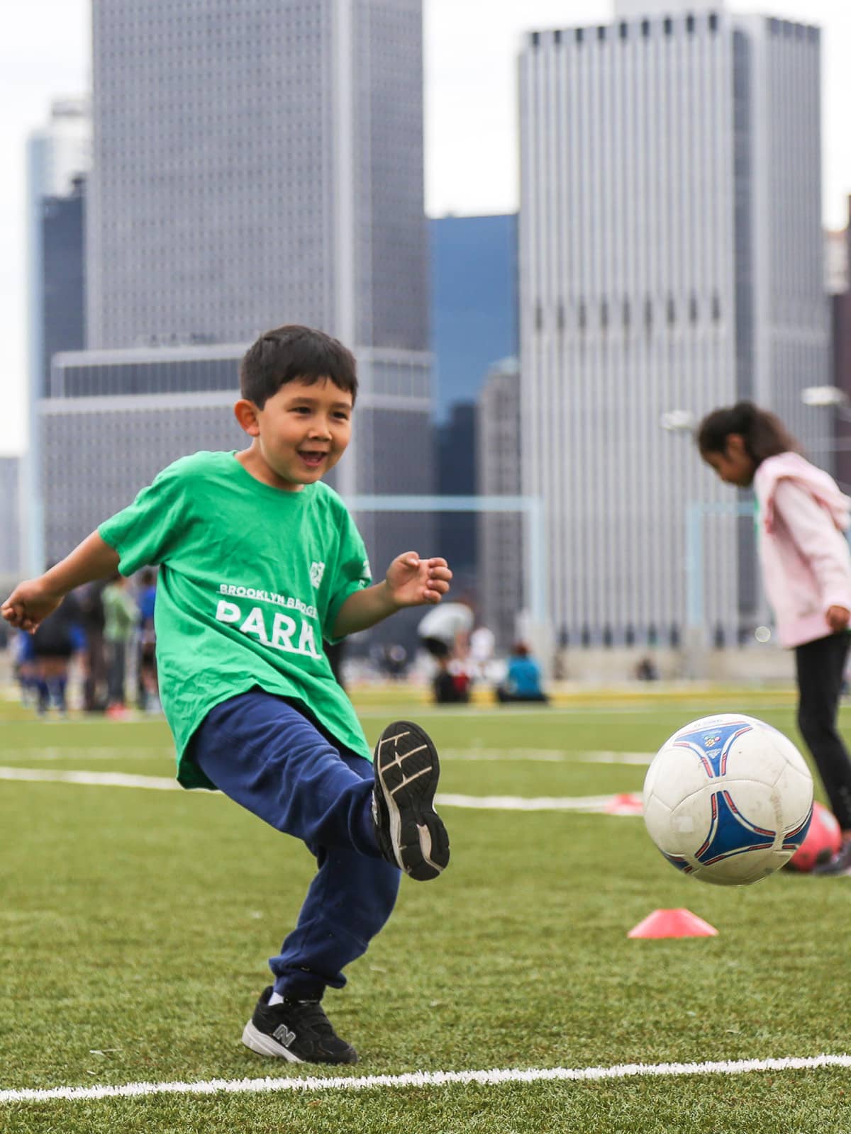 Young boy kicking at soccer ball on a cloudy day.