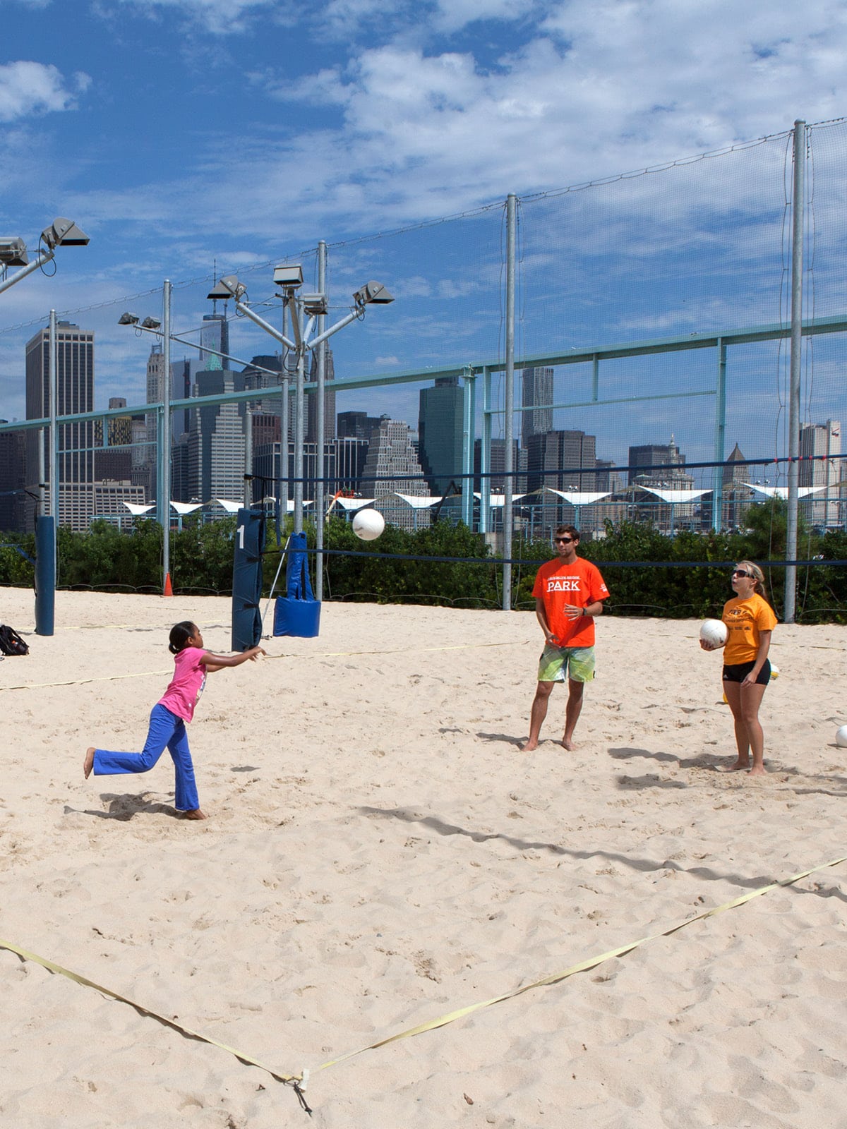 Girl hitting volleyball on a sand court at Pier 6 on a sunny day.